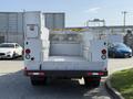 A 2015 Ford F-550 utility truck with a flatbed and toolbox compartments in a rear view
