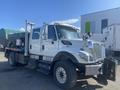A white 2014 International 7400 truck with a flatbed and mounted equipment in the back facing slightly to the right