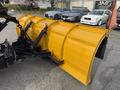 A bright yellow snow plow attached to a truck with hydraulic arms for lifting and lowering the plow blade