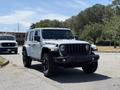 A 2021 Jeep Wrangler Rubicon with a black front grille and off-road tires is parked on a road