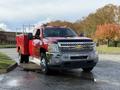 A red 2013 Chevrolet Silverado 3500HD pickup truck with a chrome grille and a flatbed attachment is parked in the foreground