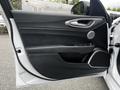 The interior door panel of a 2023 Alfa Romeo Giulia featuring sleek black leather, control buttons, and a circular speaker design