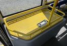 A yellow perforated metal platform inside a bus with a vertical support pole attached