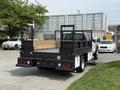 A 2008 Ford F-550 flatbed truck with a wooden platform and metal railings at the rear