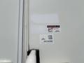 Close-up of a white exterior wall featuring service stickers from various companies and a Route 66 Network sticker on a 2018 Westland Travelaire camper