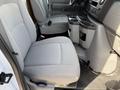 Interior view of a 2023 Ford E-450 showing two gray fabric seats and a central console with cup holders