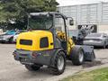 A yellow 2014 Wacker Neuson WL34 compact wheel loader with a bucket attachment displayed in a parking area