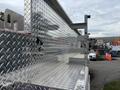 A 2002 GMC C7500 with a shiny aluminum diamond plate bed displaying several tool compartments and mounting brackets