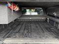 A 2018 Chevrolet Colorado truck bed with a rubber mat and a fire extinguisher mounted on the side