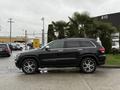 A black 2019 Jeep Grand Cherokee parked on a concrete surface with a smooth, modern design and large alloy wheels