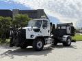 A 2016 Freightliner 108SD truck with a black snow plow attachment in front and a large black container on the back