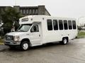 A white 2017 Ford E450 shuttle bus with large windows and a wheelchair access ramp on the side