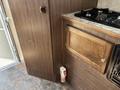 A wooden kitchenette in a 2018 Westland Travelaire featuring a gas stove top and a cabinet with a decorative handle