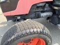 A 2010 Kubota M6040 tractor showing the engine compartment and a close-up of the front tire with a distinctive tread pattern and bright orange rim