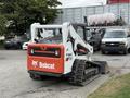 A 2017 Bobcat T740 compact track loader with a white and orange exterior and a bucket attachment at the front
