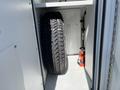 A 2013 Chevrolet Express tire stored neatly in an enclosed space with a tool visible beside it