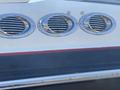 Three circular chrome vents on a white surface with a red stripe below the vents on a 2013 Larson 238 boat