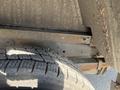 A close-up view of a 2012 Ford Econoline's undercarriage showing a metal frame and a tire with distinct tread patterns