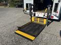 A 2017 Ford Transit-350 equipped with a wheelchair lift featuring a black mesh surface and bright yellow safety edges