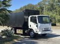 A 2016 Isuzu NPR-HD truck with a white cab and a large black dumpster container on the back