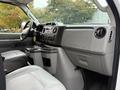 Interior of a 2019 Ford Econoline featuring a gray dashboard with controls and cup holders alongside leather seats