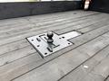 Black trailer hitch mounted on a flatbed truck bed with grooves in the wood surface around it