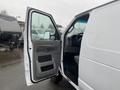 A white 2011 Ford Econoline van with an open driver's side door showing the interior and steering wheel