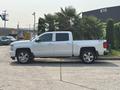 A white 2017 Chevrolet Silverado 1500 pickup truck is parked, featuring four doors and chrome wheels