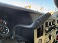 Close-up of the gear shift lever of a 2020 Chevrolet Express with buttons for shifting gears and nearby dashboard controls and gauges