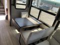 A dining area featuring a rectangular black table with two light-colored chairs positioned around it in a recreational vehicle