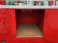 An empty storage compartment of a red 2001 Toyota Dyna with a diamond plate metal top and wooden base