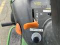 Close-up of the control panel of a 2021 John Deere L Series lawn mower featuring an orange choke lever and various labeled dials and switches