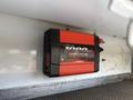 A red and black power inverter labeled 1000W mounted inside a vehicle