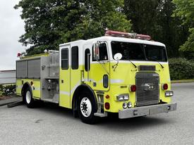 A 1995 Freightliner FLL086 fire truck painted bright yellow with outfitted equipment and a red light bar on top