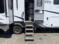 A 2021 Grand Design Recreational ST3478MBS with a set of steps leading up to the entrance and a door partially open