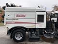 A 2009 UD Trucks UD 3300 street sweeper with a white body and Elgin branding featuring a large sweeping brush on the front and a vacuum system on the side