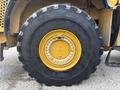 A large black tire with a yellow rim featuring bolts and a smooth surface typical of heavy machinery like a Caterpillar 980