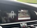 A 2023 Alfa Romeo Giulia displayed on a car dashboard screen showing a rearview camera with guidelines for parking assistance