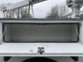 A 2012 Ford F-450 SD truck bed with an open storage compartment and chains hanging from the sides