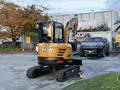 A yellow 2023 Sany SY35U mini excavator with a compact design and tracks stands in the foreground showcasing its articulated arm and bucket