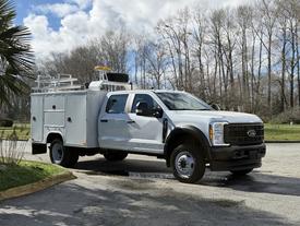 A 2024 Ford F-550 with a service body and utility features parked at an angle with clear visibility of its front and side