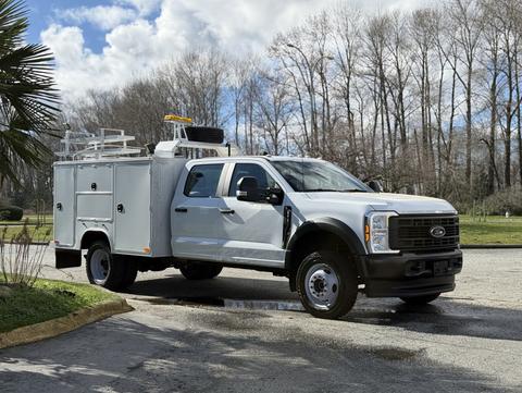 A 2024 Ford F-550 with a service body and utility features parked at an angle with clear visibility of its front and side