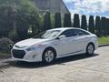 A white 2014 Hyundai Sonata parked with its headlights on and distinctive design features including a sleek body and aerodynamic shape