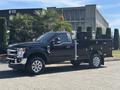 A 2022 Ford F-350 Super Duty truck with a black exterior and a flatbed design featuring storage boxes on both sides
