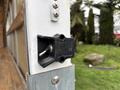 A close-up view of a latch mechanism on the door of a 2024 Ford E-450 with water droplets on its surface