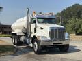 A white 2008 Peterbilt 340 truck with a large cylindrical tank attached to its rear and multiple amber lights on the roof