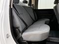The interior of a 2013 RAM 3500 featuring a spacious back seat with gray fabric upholstery and seat belts installed
