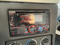 A Kenwood DPX404BT car stereo displaying the time and radio station with illuminated buttons and knobs for radio controls and volume adjustment