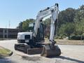 A 2010 Bobcat E80 excavator features a white and black body with a large articulated arm and bucket for digging and earth-moving tasks