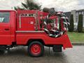 A red 2001 Toyota Dyna fire truck with a hose reel mounted on the side and firefighting equipment visible on the back